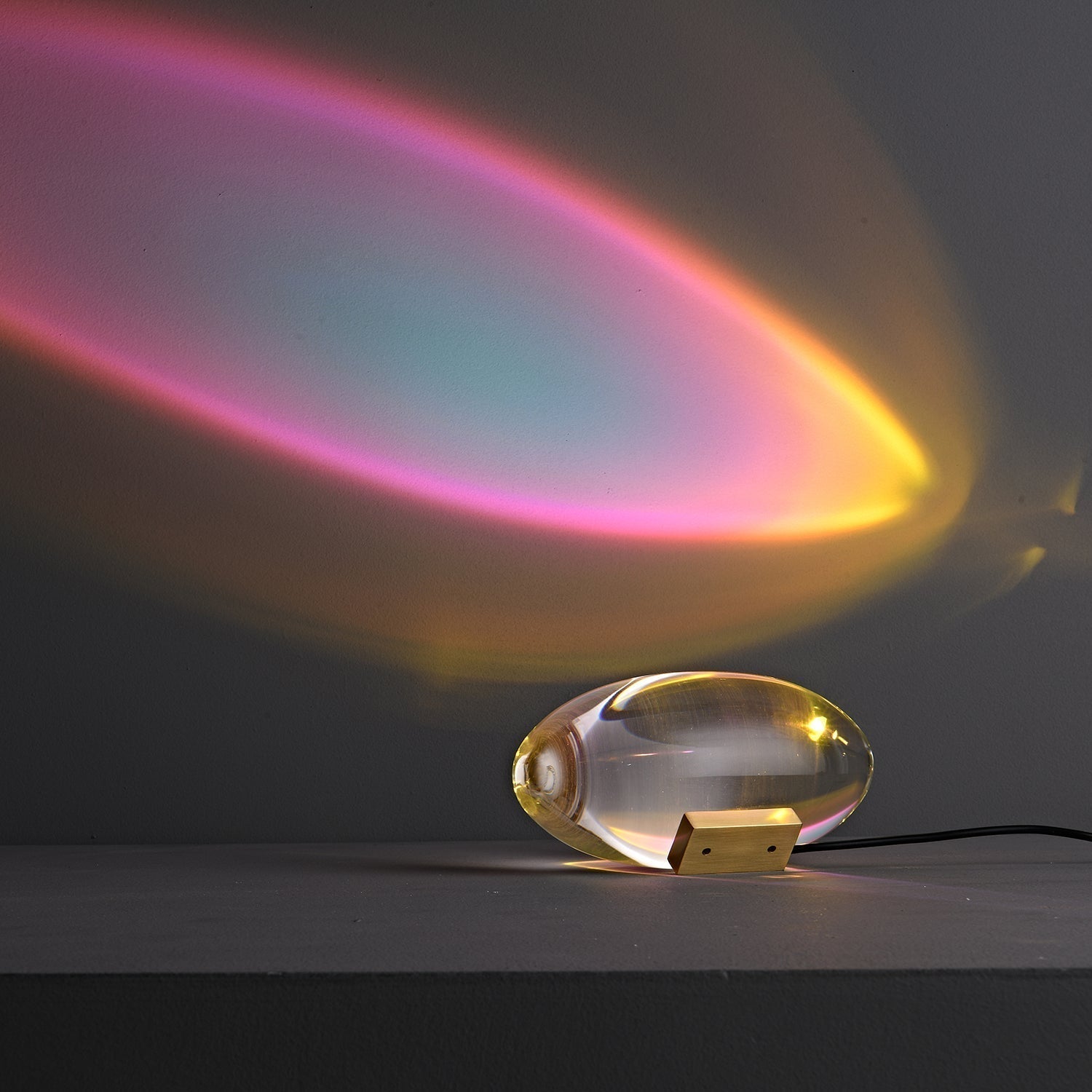 Oval dekorativ bordlampe med transparent linseformet krop og indvendig glød