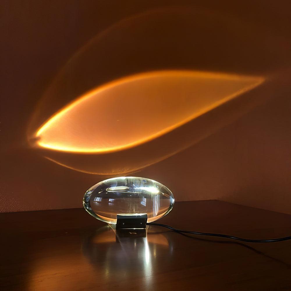 Oval dekorativ bordlampe med transparent linseformet krop og indvendig glød