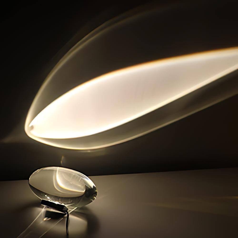 Oval dekorativ bordlampe med transparent linseformet krop og indvendig glød