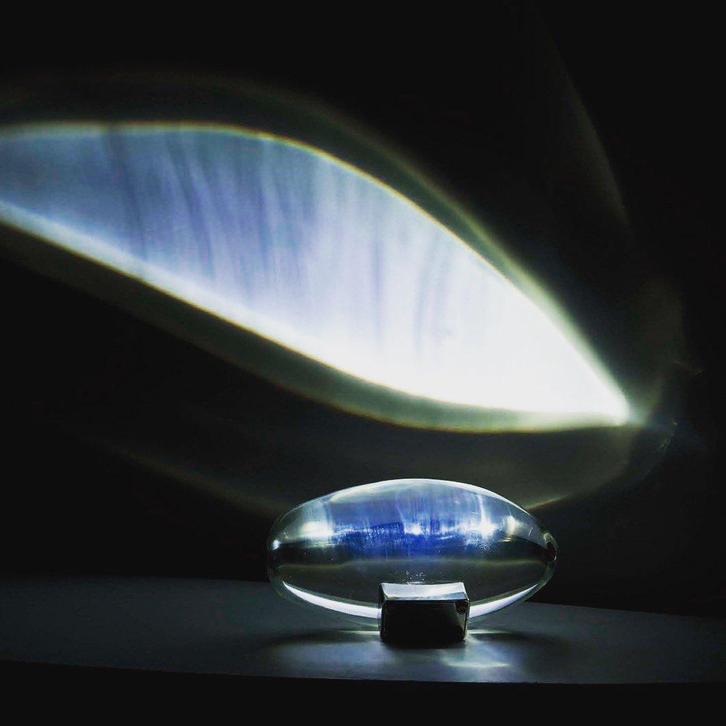 Oval dekorativ bordlampe med transparent linseformet krop og indvendig glød