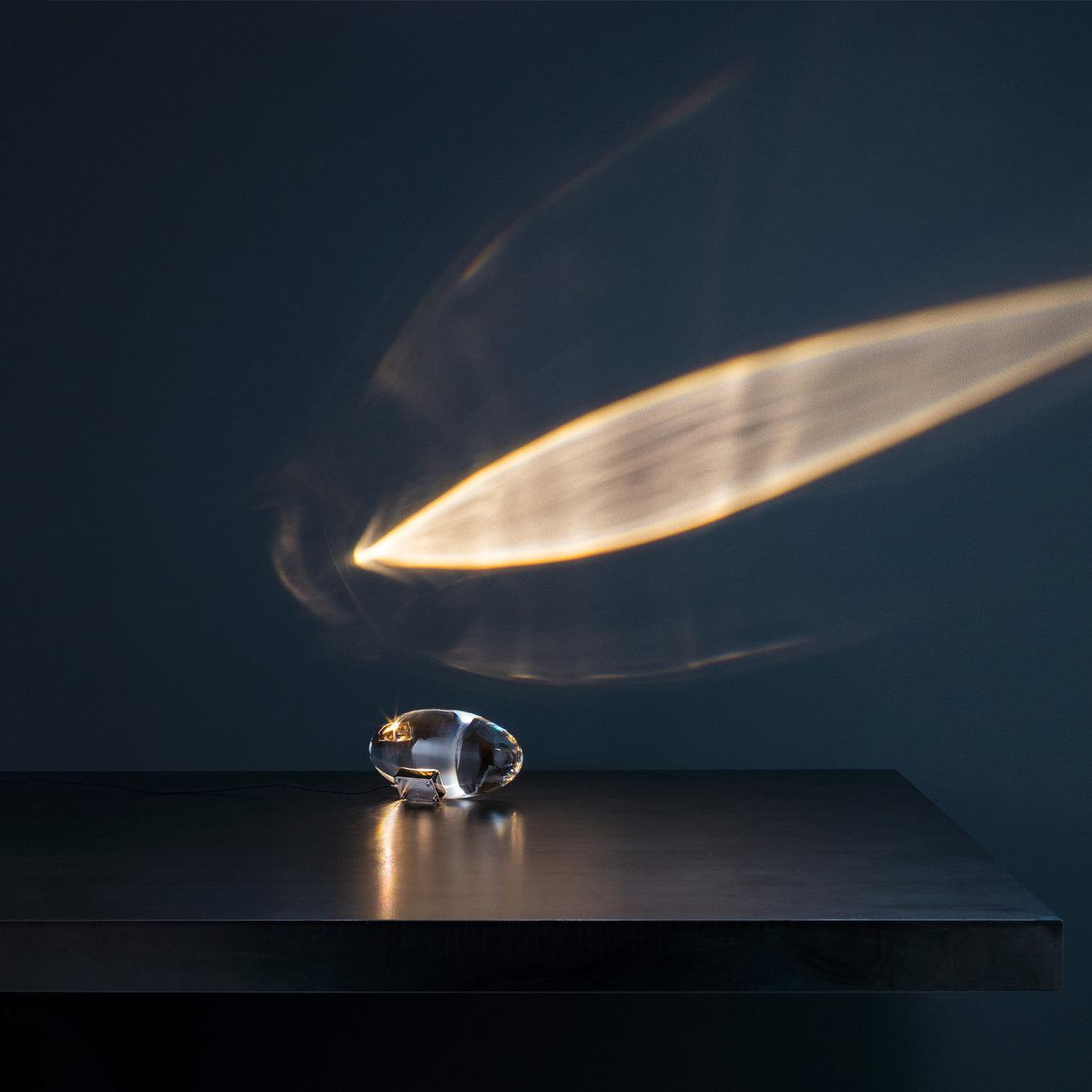 Oval dekorativ bordlampe med transparent linseformet krop og indvendig glød