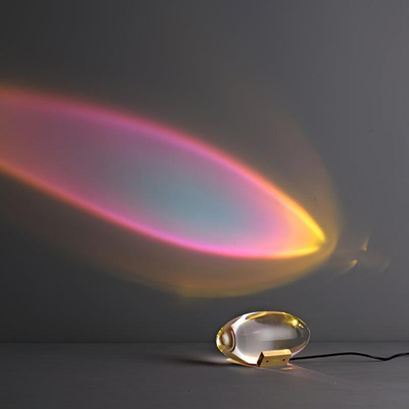 Oval dekorativ bordlampe med transparent linseformet krop og indvendig glød