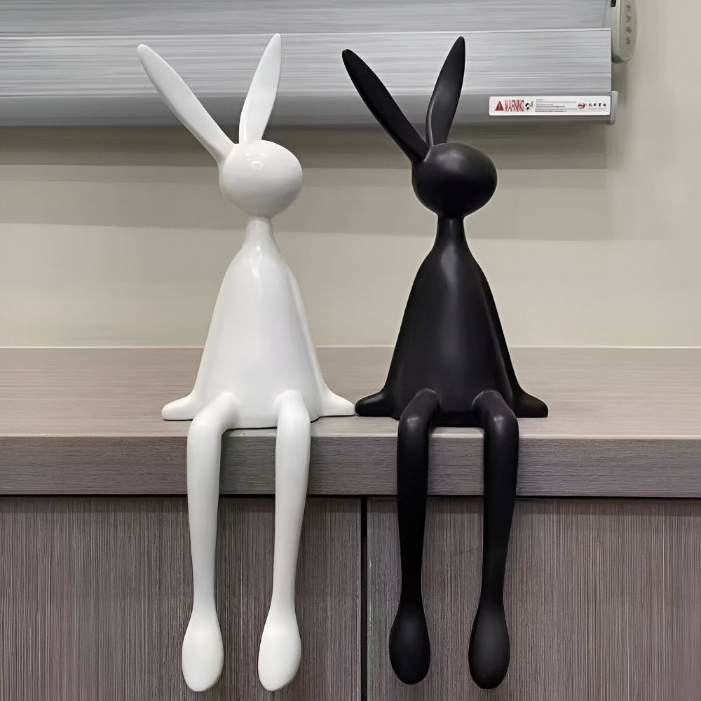 Siddende kaninfigur i harpiks med hængende ben